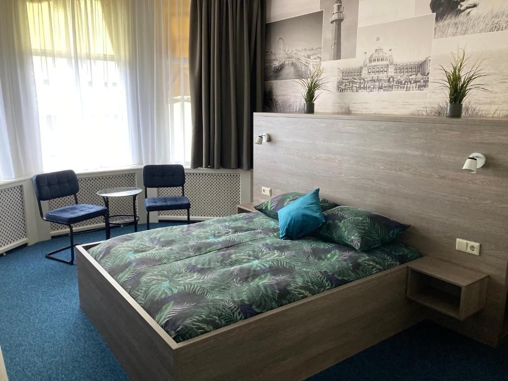 a bedroom with a large bed with blue pillows at Hotel Poseidon in Scheveningen