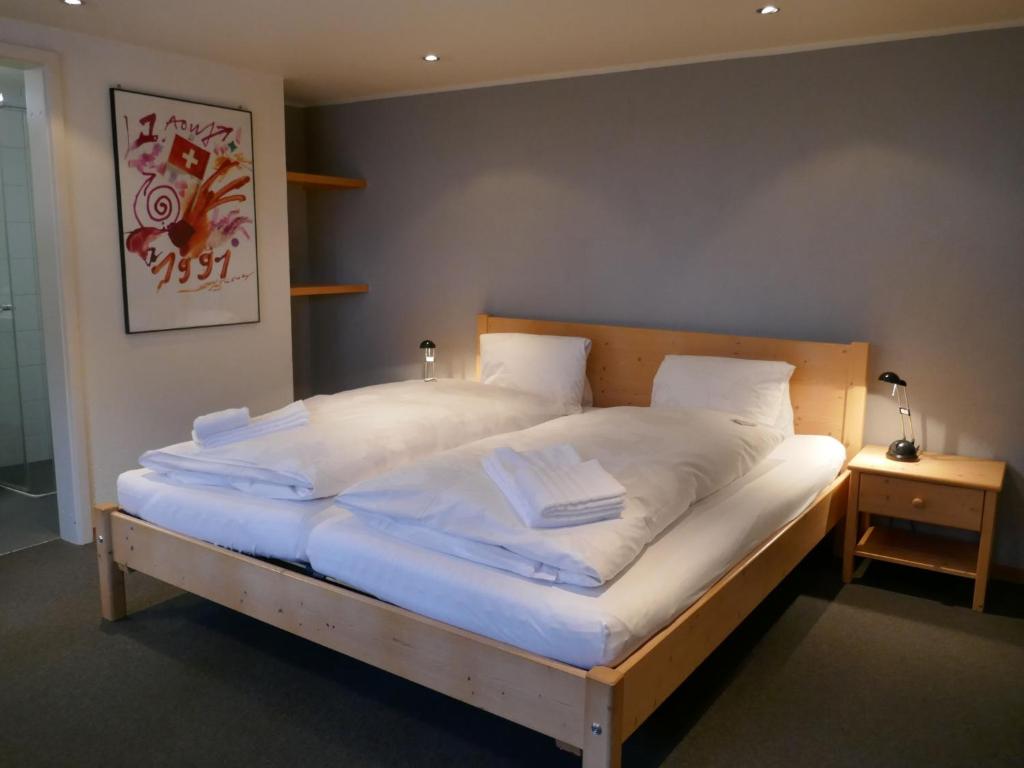 ein großes Bett mit weißer Bettwäsche und Kissen darauf in der Unterkunft Apartment Chalet Schwendihus-6 by Interhome in Grindelwald