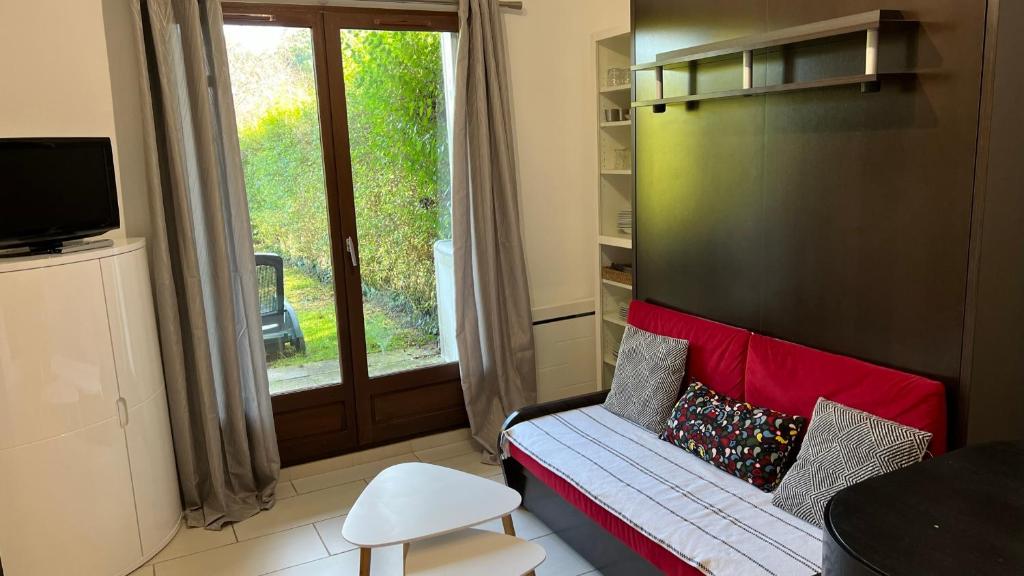 uma pequena sala de estar com um sofá e uma janela em Appartement 2 pièces rez-de-jardin à 2 pas de la plage et de la thalasso em Cabourg