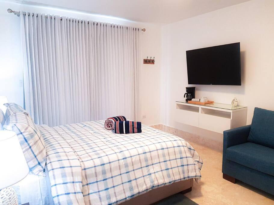 a bedroom with a bed and a tv and a blue chair at Playa Dorada Suites in San Felipe de Puerto Plata