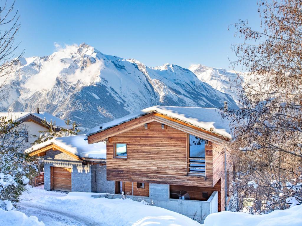 a log home in the snow with mountains in the background at Chalet Woovim 8 by Interhome in Nendaz