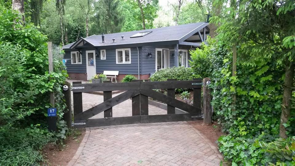ein kleines blaues Haus hinter einem Holztor in der Unterkunft Heerlijk huis in een prachtige bosrijke omgeving. in Putten