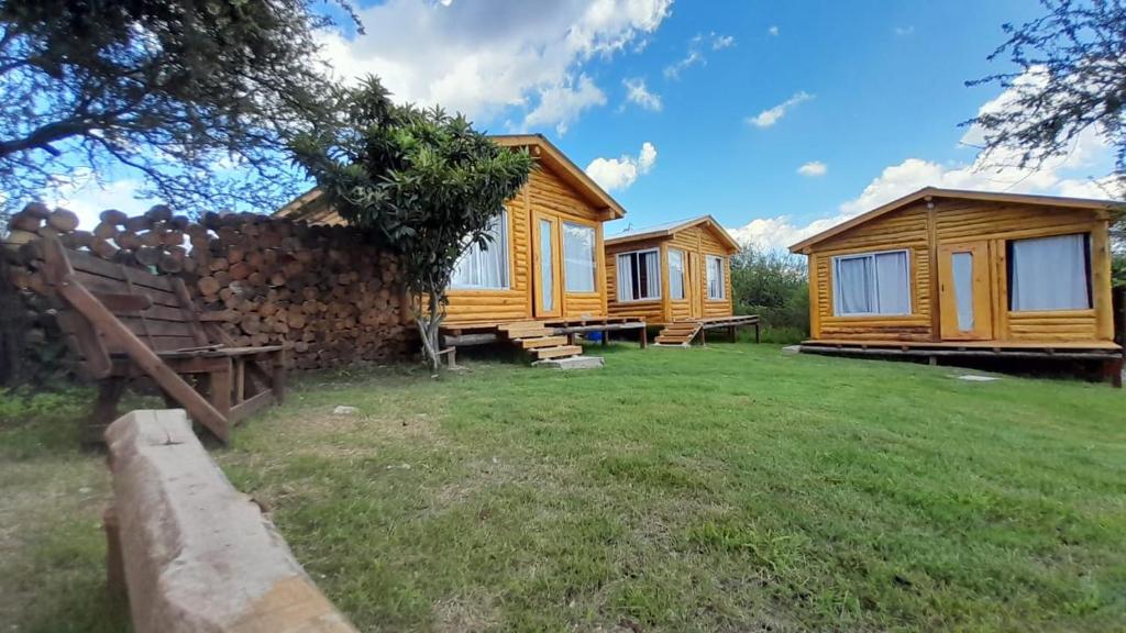 una fila de cabañas de madera en un patio en Complejo majua en Cosquín