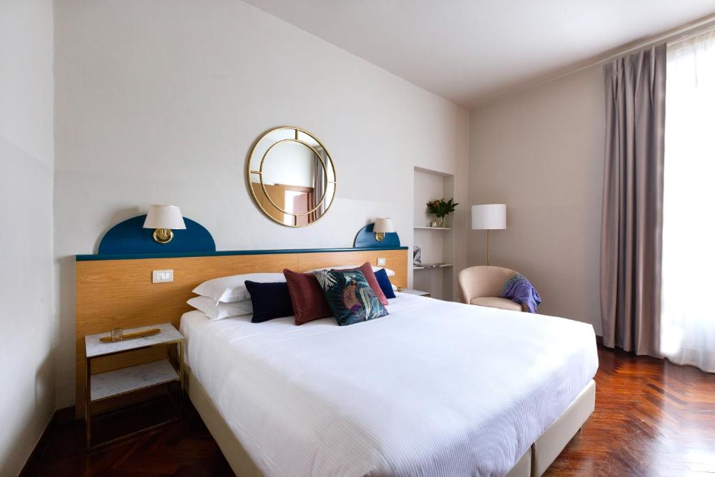 1 dormitorio con 1 cama blanca grande y espejo en Aramis Rooms, en Florencia