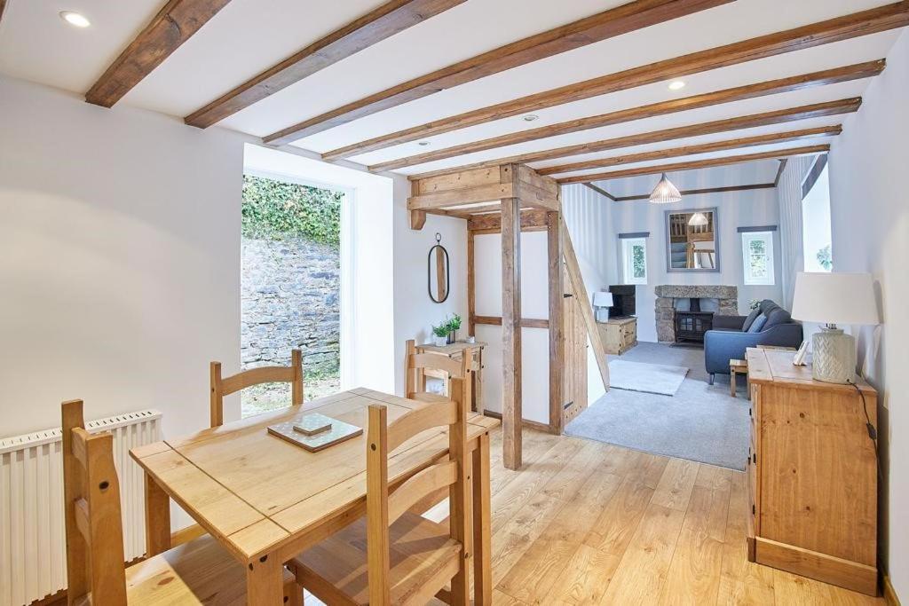 een eetkamer met een tafel en een woonkamer bij Woodland cottage in Cornwall with walled garden in Helston