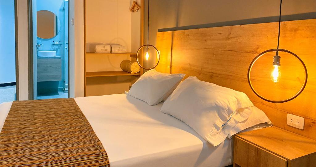 a bedroom with a white bed with a wooden headboard at Hotel Ruittoque D Prada in Bucaramanga