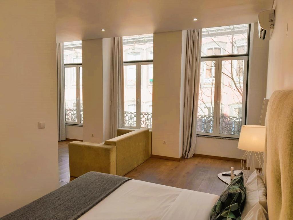 a bedroom with a bed and a couch and windows at Asgard Oporto Downtown Apartments in Porto