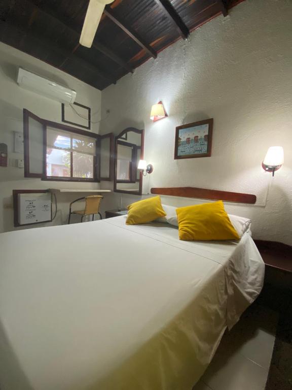 a bedroom with a large white bed with yellow pillows at Hotel Nueva Granada in Santa Marta