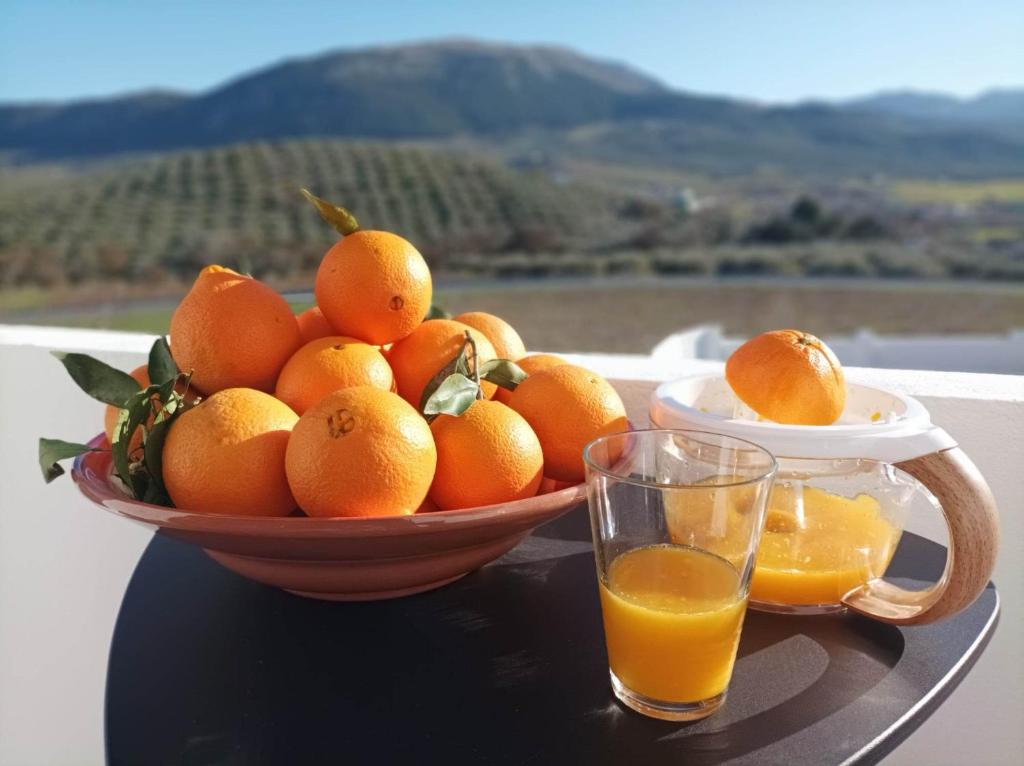 een kom sinaasappels op een tafel met een glas sinaasappelsap bij Casa Celeste Trabuco in Villanueva del Trabuco