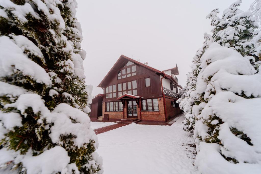 una casa en la nieve con árboles nevados en Vila LALUKO en Zlatibor