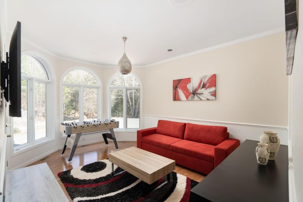 uma sala de estar com um sofá vermelho e uma mesa em Majestic Retreat in the Laurentians em Morin Heights