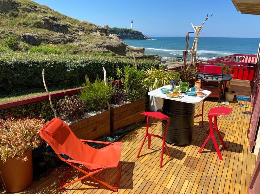 un patio avec une table et des chaises et l'océan dans l'établissement T3 VUE MER A 20 mètres de la PLAGE ANGLET BIARRITZ, à Anglet