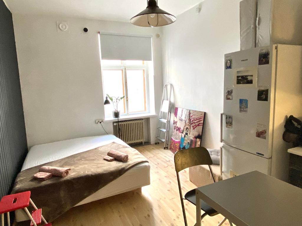 a small room with a bed and a table and a refrigerator at Bohemian studio in Etu-Töölö in Helsinki