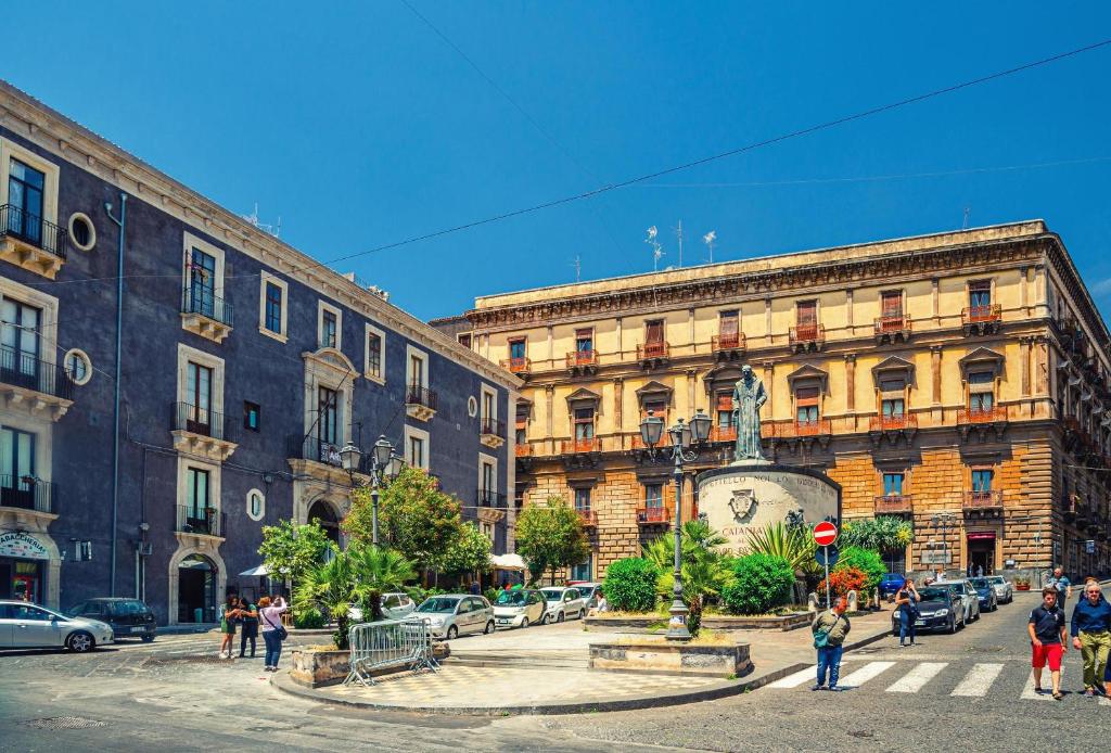 una via cittadina con edifici e una statua al centro di Appartamento Don Tano a Catania