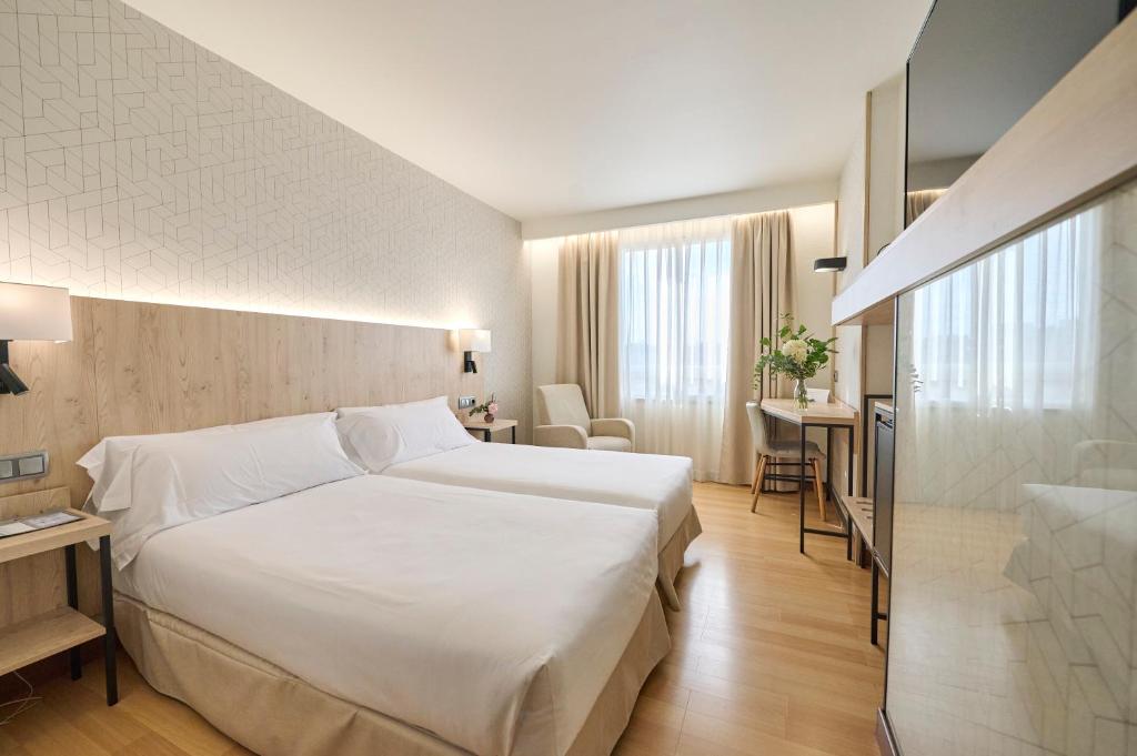 Hotel Albret في بامبلونا: غرفة في الفندق مع سرير أبيض كبير ومكتب
