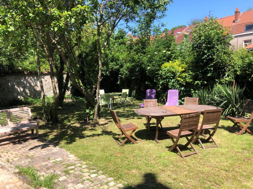 - une table et des chaises en bois dans la cour dans l'établissement Appartement meublé proximité plage Malo les bains, à Dunkerque
