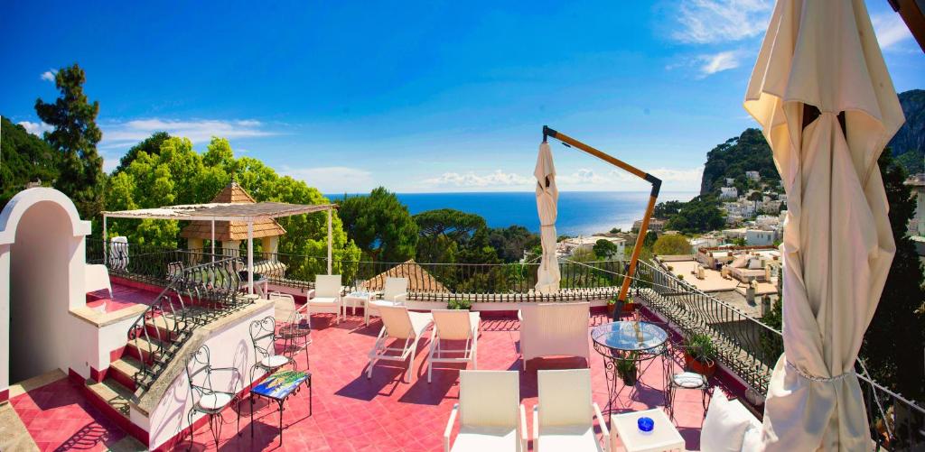 Un balcón con sillas y mesas y vistas al océano. en Villa Silia, en Capri