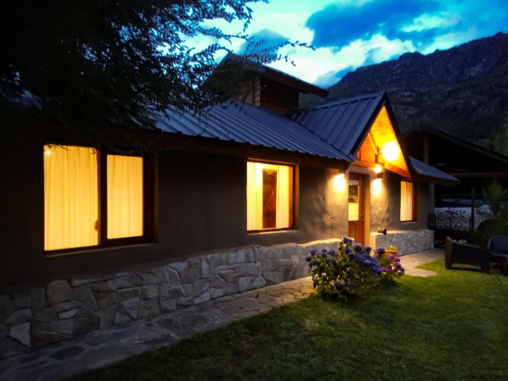 a house lit up at night with lights at Vuelvo al Sur Alojamiento Lago Puelo in Lago Puelo