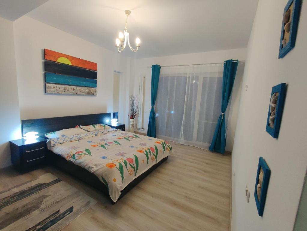 Schlafzimmer mit einem Bett und einem Fenster mit blauen Vorhängen in der Unterkunft Amira Apartament in Constanţa