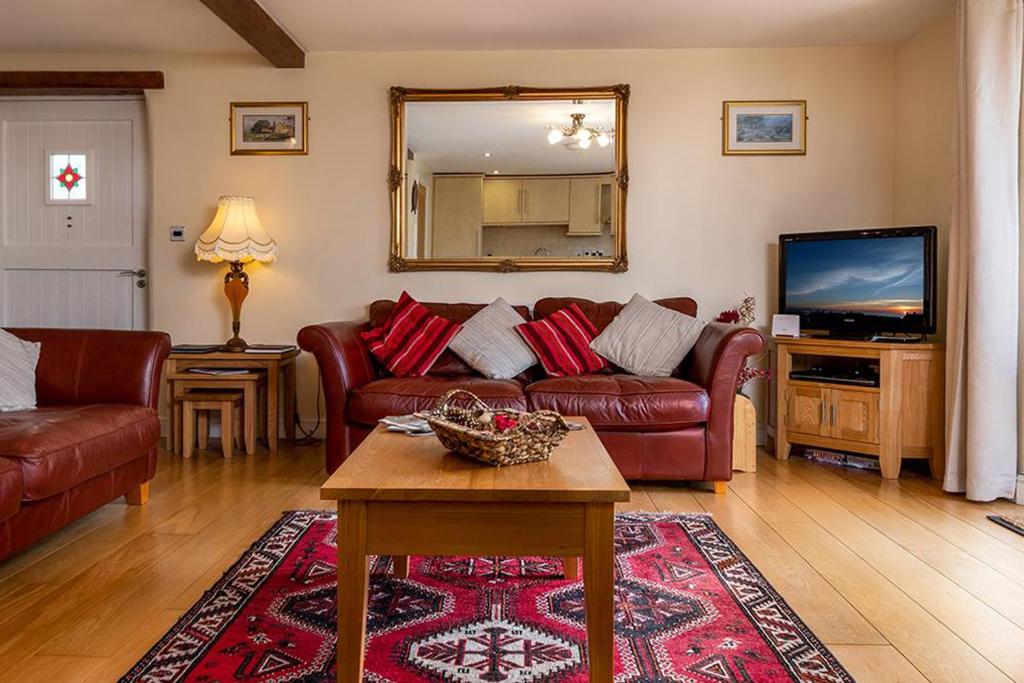 ein Wohnzimmer mit einem Sofa und einem TV in der Unterkunft Tregarnedd Cottage in Llangefni