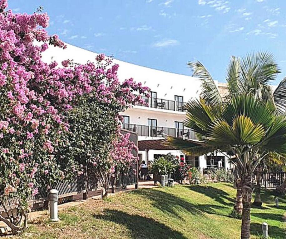 ein großes Gebäude mit rosa Blumen davor in der Unterkunft 2 Bedrooms 2 Bathrooms pool view apartment in Santa Maria