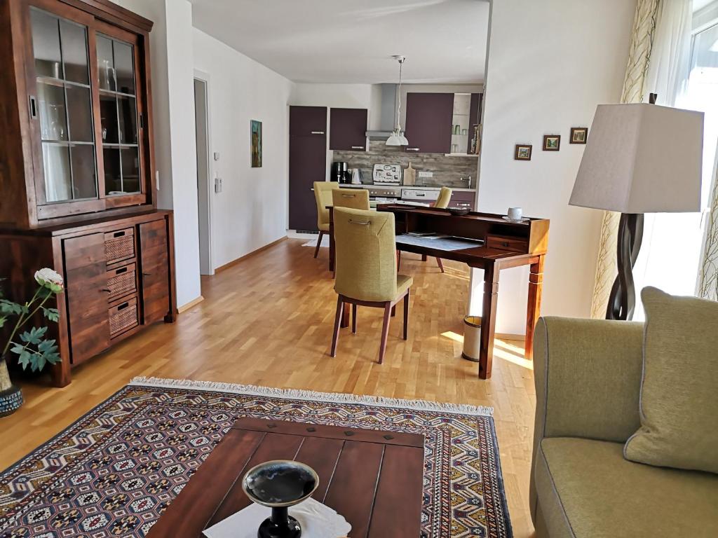 ein Wohnzimmer mit einem Tisch und Stühlen sowie eine Küche in der Unterkunft Apartment Velden - Angelika Berginz in Velden am Wörthersee