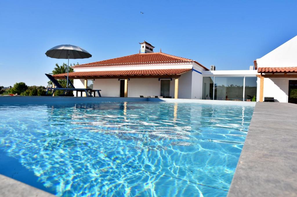 a swimming pool in front of a house at Monte Casa Branca in Montemor-o-Novo