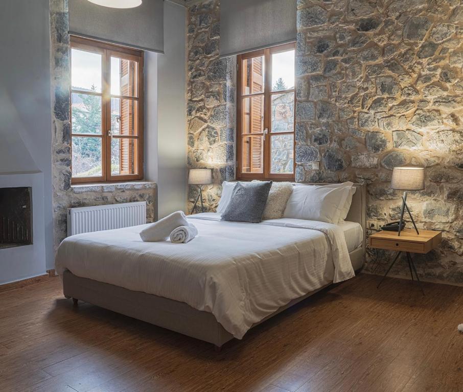 a bedroom with a large bed and a stone wall at Anastasia's Suites Arcadia in Vytina