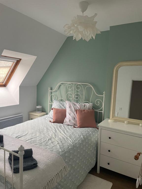 a bedroom with a bed and a dresser with a mirror at Cocon douillet en bord de mer in Grandcamp-Maisy