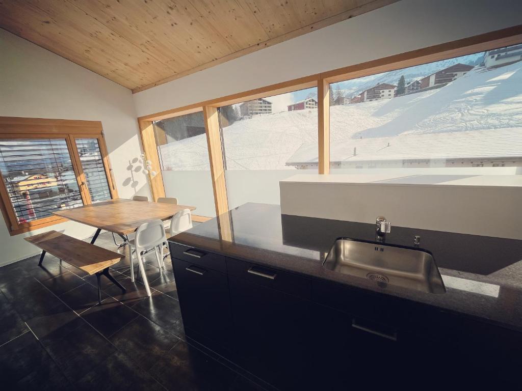 3 bedroom condo in front of Obersaxen ski resort في أوبرساكسن: مطبخ مع حوض وطاولة مع نافذة
