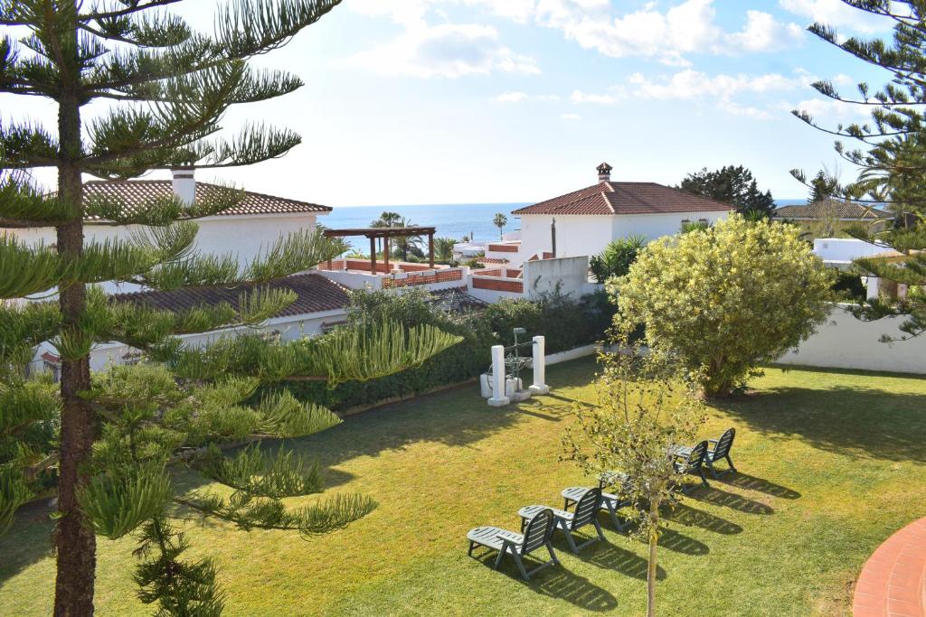 un jardín con bancos y vistas al océano en Villa María Elena, en Fuente del Gallo, en Conil de la Frontera