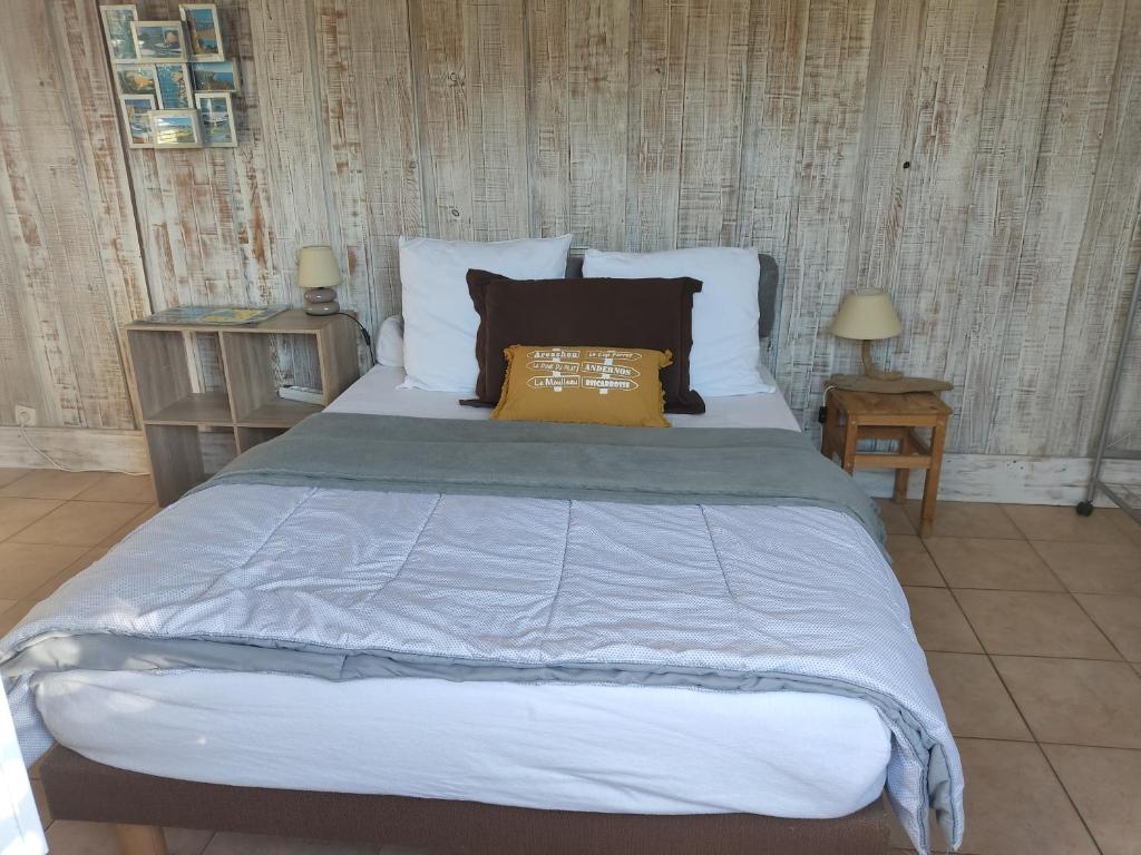 a bedroom with a large bed with blue sheets and pillows at Les Cigales du Bassin in Gujan-Mestras