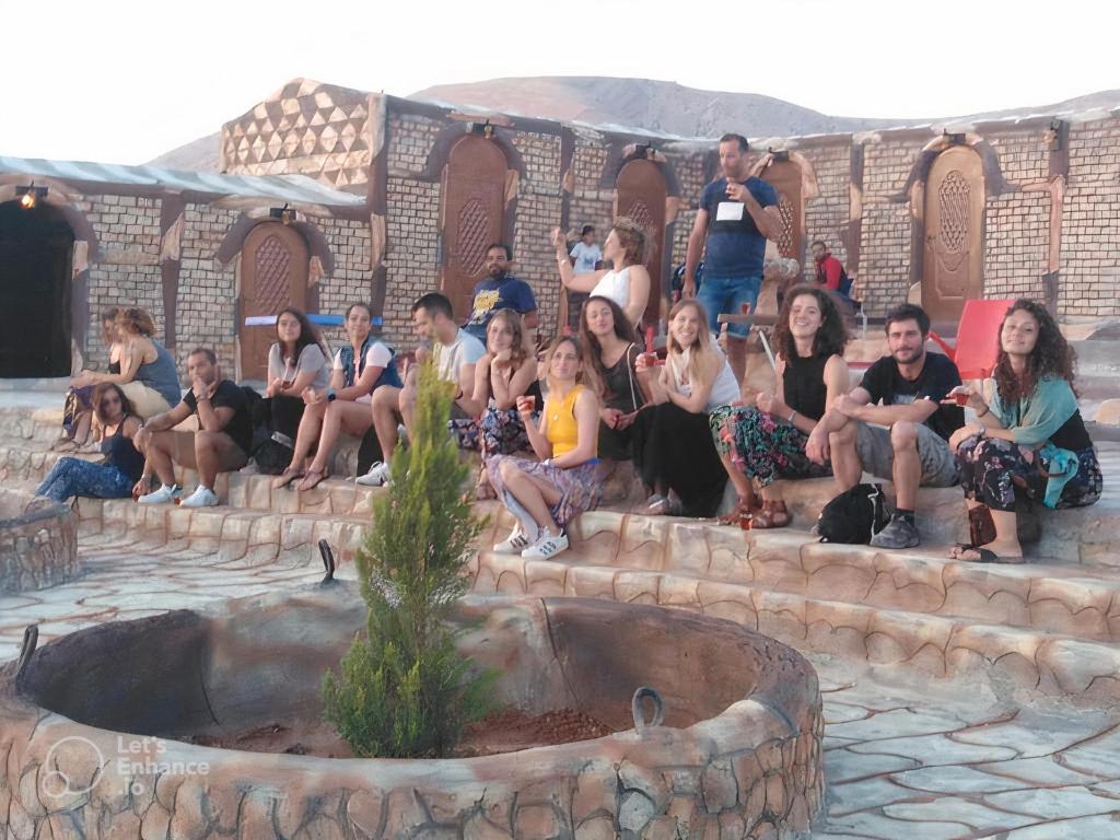 een groep mensen die op een trap naast een fontein zitten bij Little Petra Heritage Village in Wadi Musa