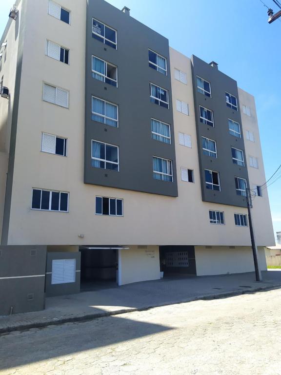 un edificio de apartamentos con un aparcamiento enfrente en Apartamento no Mar Grosso em Laguna SC. en Laguna