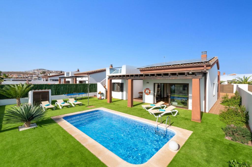 un patio trasero con piscina y una casa en Villa Fakay by Villa Plus en Caleta de Fuste