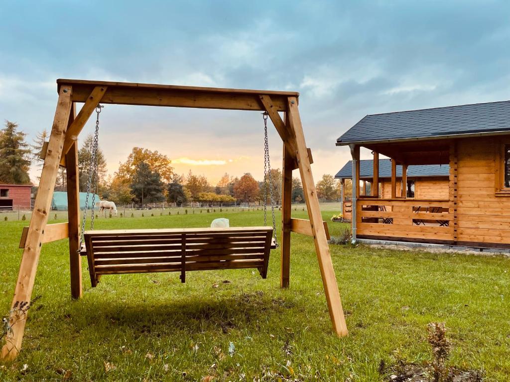 un columpio de madera en un patio con una cabaña en JZ Guest Ranch, en Woldenberg Neumark