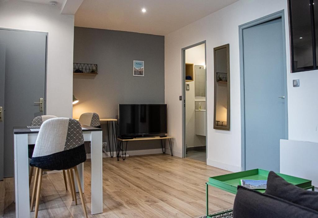 a living room with a table and a tv at Appart Saint Cyprien + Parking privatif in Poitiers