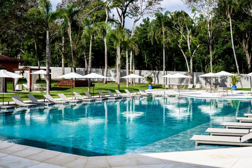 a large swimming pool with lounge chairs and umbrellas at Sanma Hotel in Foz do Iguaçu