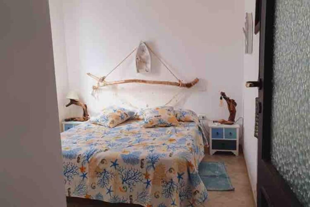 a bedroom with a bed with a large headboard at Sant Antioco, la vista sulla laguna Q2127 in SantʼAntìoco
