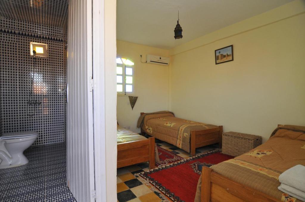 una camera con 2 letti e una vasca e una doccia di Riad Freija-TAROUDANT a Sidi Abd el Kader