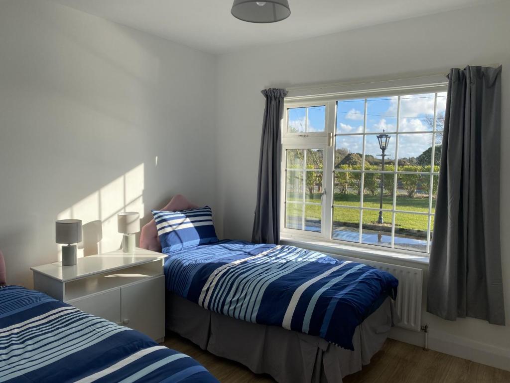 een slaapkamer met 2 bedden en een raam bij Lake Big, Five Bedroom Holiday Home Rosslare Strand, County Wexford in Mervyn