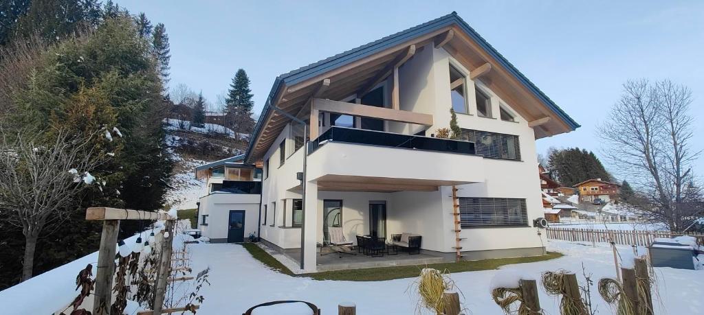 une maison blanche sous la neige avec des arbres dans l'établissement Apartment auf der Schladminger Sonnenseite - smart, zentral & ruhig, à Schladming