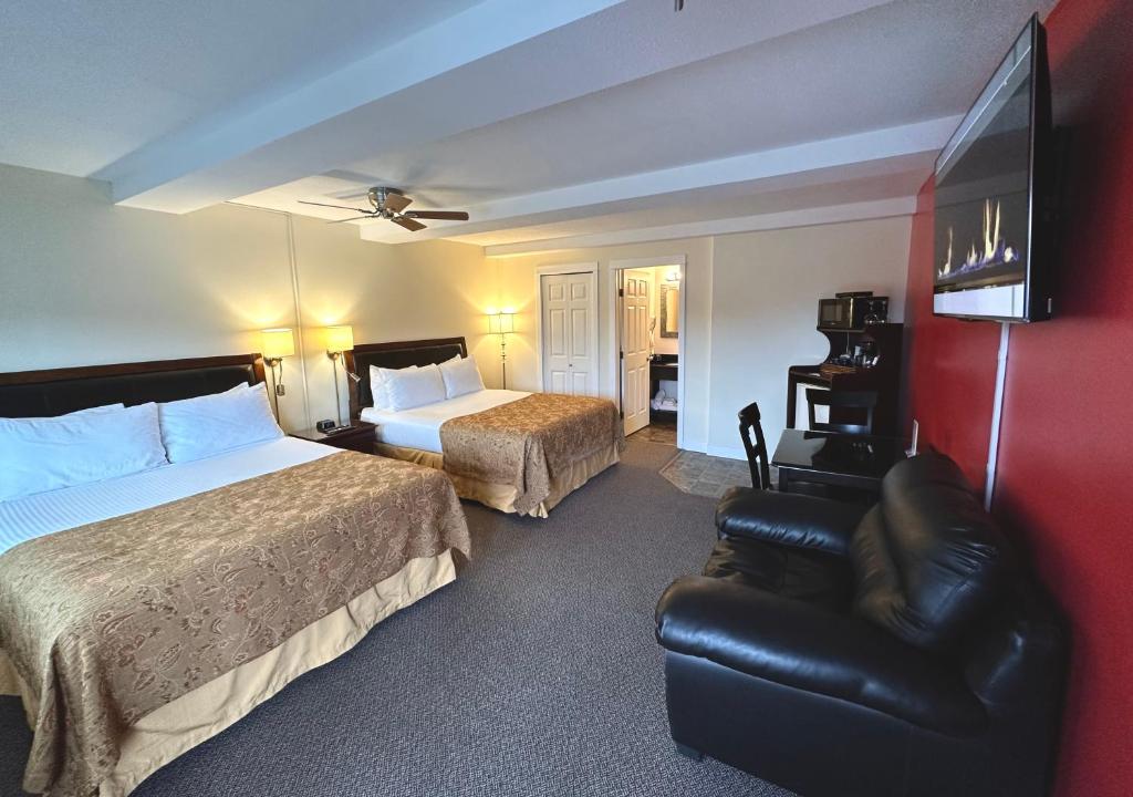 a hotel room with two beds and a leather chair at Bayshore Waterfront Inn in Ucluelet