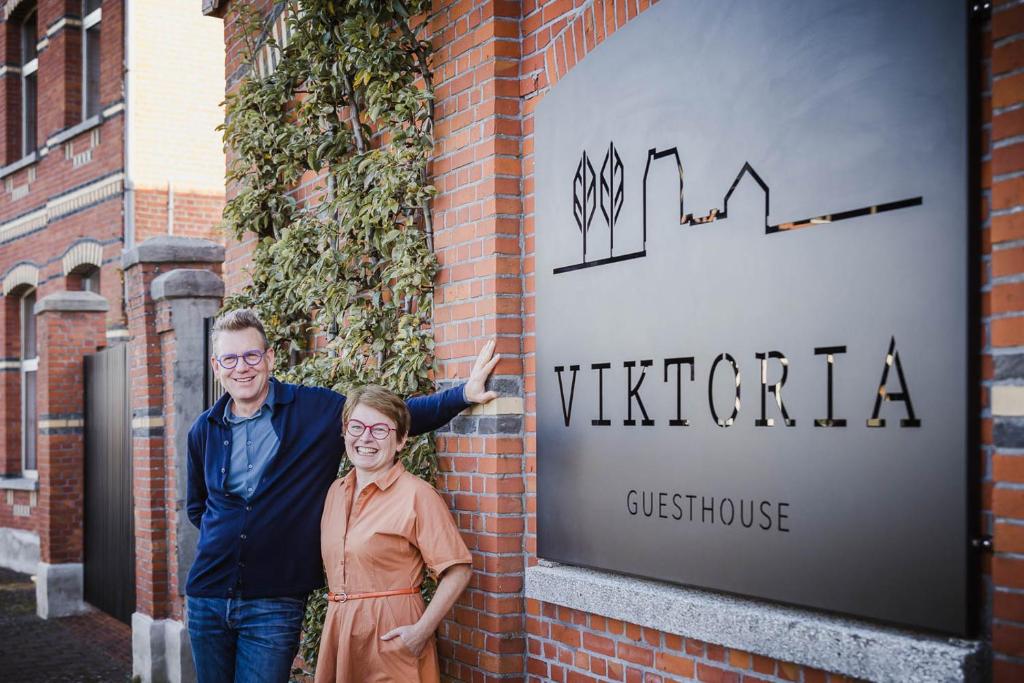 un hombre y una mujer parados frente a una señal en Viktoria Guesthouse, en Westerlo