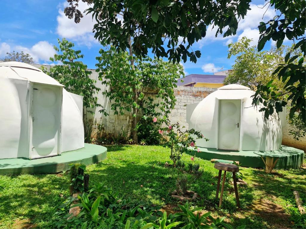 twee witte koepels in een tuin met een hek bij Hospedagem Alternativa in Alto Paraíso de Goiás