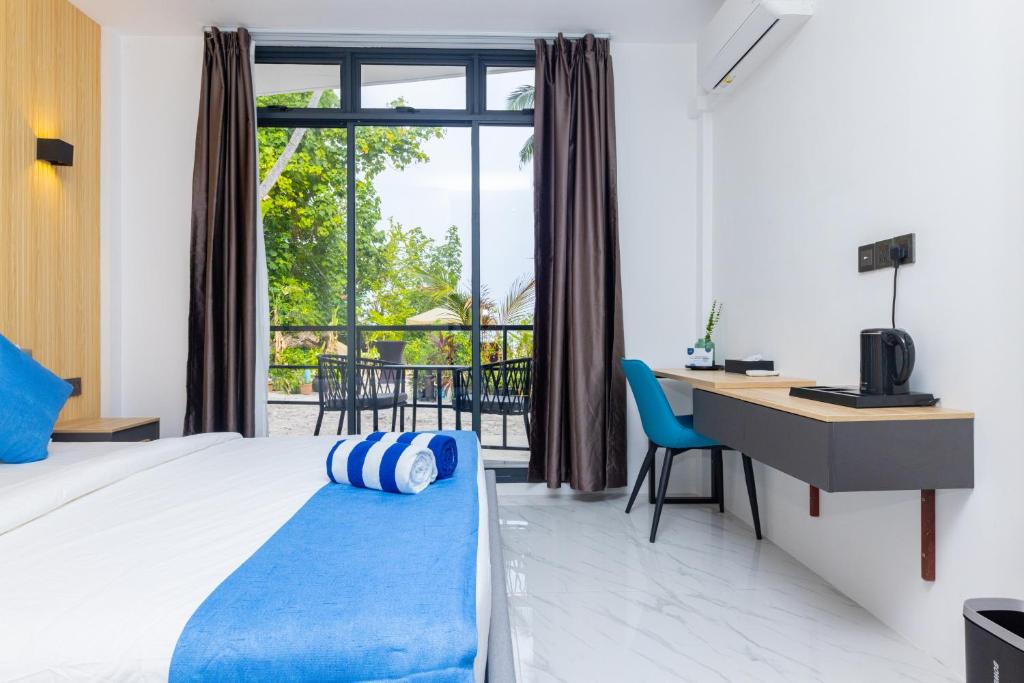 een hotelkamer met een bed, een bureau en een raam bij Atoll Residence Dhangethi in Dhangethi