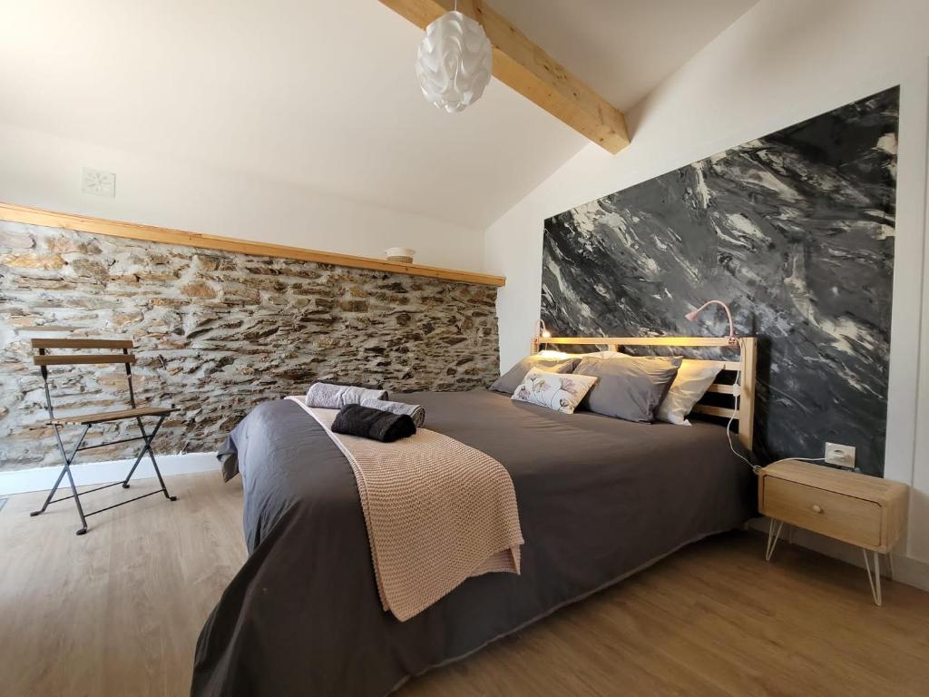 1 dormitorio con 1 cama grande y pared de piedra en Casa da Memória en Milhão