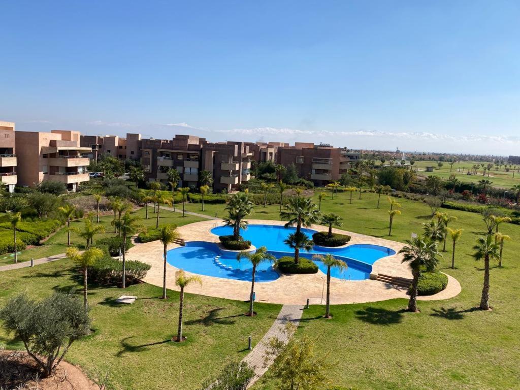 - une vue sur la piscine bordée de palmiers et de bâtiments dans l'établissement Prestigia jade Marrakech ENTREE 191 APPARTEMENT 9, à Marrakech