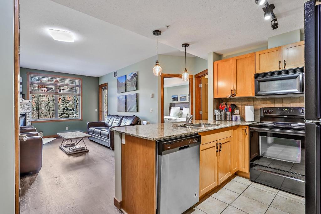een keuken met houten kasten en een woonkamer bij Fenwick Vacation Rentals Inviting Rocky Mountain HOT TUB in Top Rated Condo in Canmore