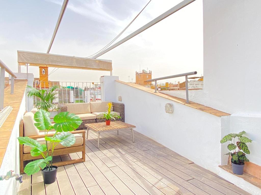 een balkon met een bank, een tafel en planten bij Apartamentos Giralda, centro Histórico Sevilla in Sevilla